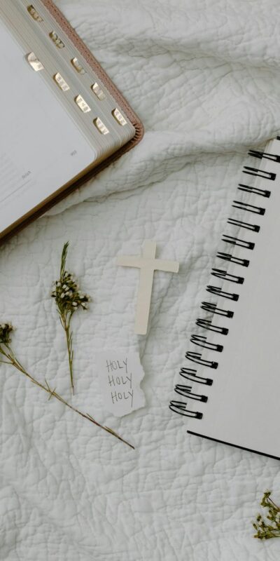 A flat lay of an open Bible and a blank notebook on a quilt, symbolizing faith and reflection.