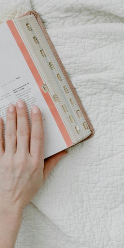 Top view of morning Bible study with coffee, featuring open Bible and feminine hands.